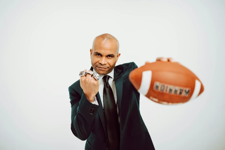 a man in a suit holding a football, alexis franklin, point finger with ring on it, full product shot, wearing presidential band