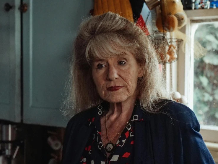 a woman standing in a kitchen next to a window, a portrait, by Georgina Hunt, pexels contest winner, portrait of dolly parton, still from a terence malik film, concerned expression, seaside