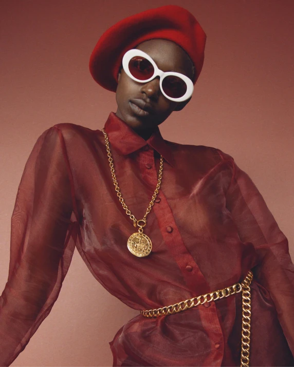 a close up of a person wearing a hat and sunglasses, an album cover, trending on pexels, afrofuturism, dressed in red velvet, nonbinary model, gold chain belt, delicate androgynous prince