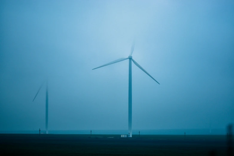 a group of wind turbines sitting on top of a field, by Adam Pijnacker, dark blue mist, large scale photo, pc screen image, blue gray