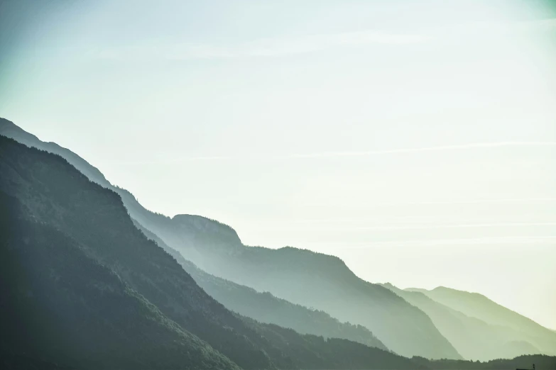 a large body of water with mountains in the background, by Johannes Voss, pexels contest winner, figuration libre, gradient green, contre jour, hillside, muted colours 8 k