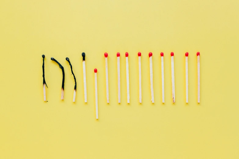 a row of matches on a yellow background, by Nicolette Macnamara, minimalism, playing with fire, tiny sticks, contracept, mixed art