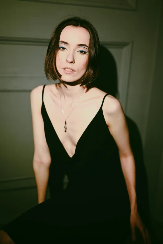 a woman in a black dress posing for a picture, inspired by Nan Goldin, lily collins, decolletage, with a bob cut, 90's color photo