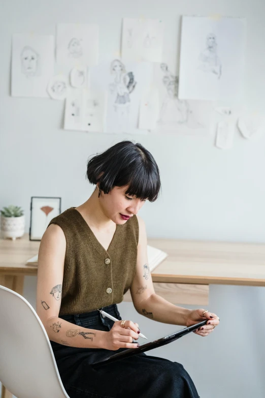 a woman sitting at a desk writing on a piece of paper, a picture, inspired by Ruth Jên, trending on pexels, with a bob cut, checking her phone, wearing a designer top, bao pham