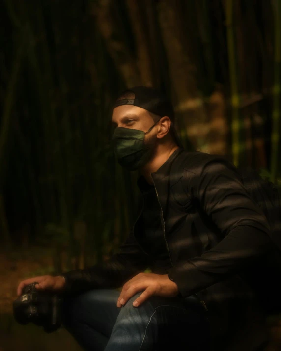 a man sitting on a bench wearing a face mask, a picture, by Attila Meszlenyi, sumatraism, dark forest theme, low quality photo, green ambient light, profile picture 1024px