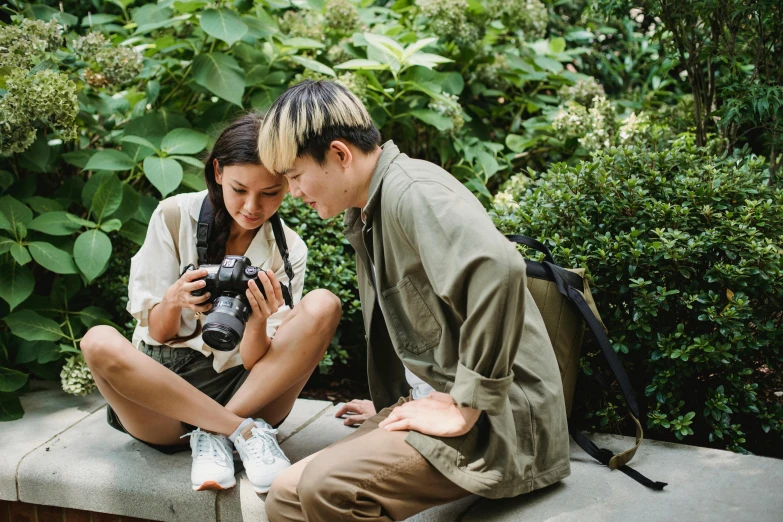 a man and a woman sitting on a bench looking at a camera, a picture, pexels contest winner, tyler edlin and natasha tan, flatlay, holding a camera, roy lichtenstein and jackie tsai