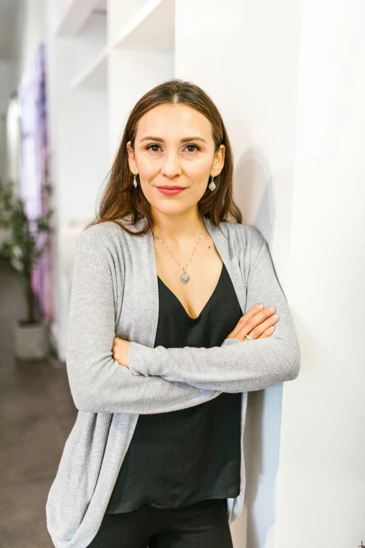 a woman leaning against a wall with her arms crossed, antipodeans, body and headshot, russian academic, vp of marketing, hasbulla magomedov