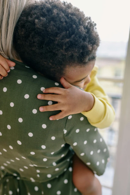 a woman holding a child in her arms, by Winona Nelson, pexels, head bowed slightly, diverse, instagram post, looking outside