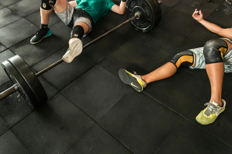 a man laying on the ground with a barbell, by Matija Jama, pexels contest winner, hurufiyya, a group of people, knees weak, pixeled stretching, boys