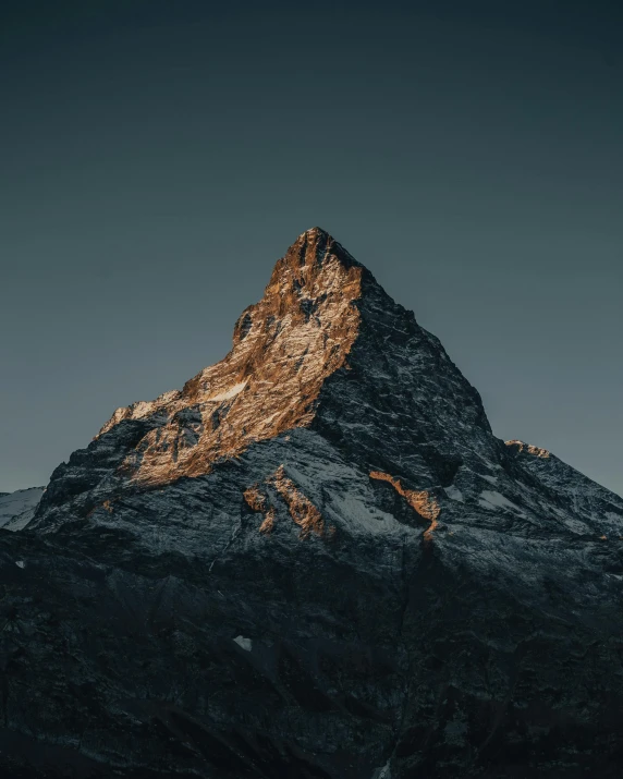 the top of a mountain covered in snow, an album cover, by Johannes Voss, unsplash contest winner, bathed in golden light, brown, dusk light, giant imposing mountain