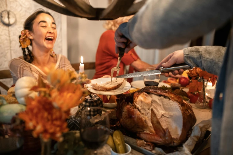 a group of people sitting around a table with a turkey, food, holding knife, profile image, thumbnail