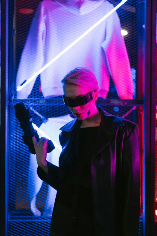 a woman holding a gun in front of a display case, cyberpunk art, inspired by ridley scott, pexels contest winner, a man wearing a black jacket, futuristic fashion show, futuristic sunglasses, blacklight aesthetic