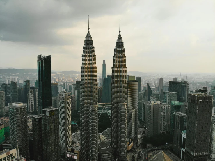 a view of some very tall buildings in a big city, by Bernardino Mei, pexels contest winner, hurufiyya, malaysian, aerial footage, tall spires, slight overcast