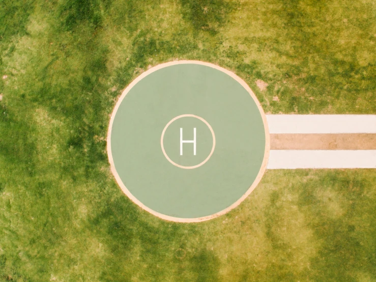 a basketball court sitting on top of a lush green field, an album cover, by Attila Meszlenyi, trending on unsplash, land art, helipad, shape of a circle, hydrogen. beautiful, holy halo