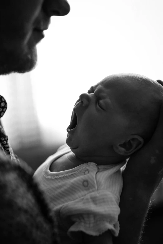 a man holding a baby in his arms, a black and white photo, by Dan Frazier, pexels contest winner, mouth shut, african aaron paul, sickness, phot