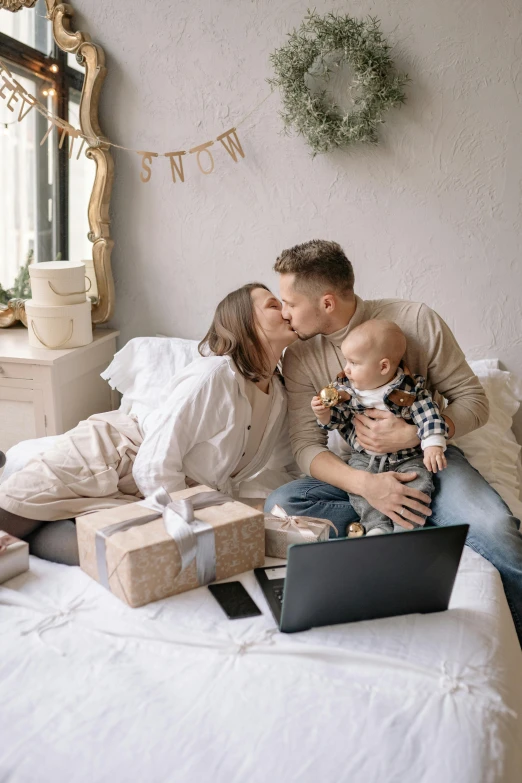 a man and woman sitting on a bed with a baby, pexels contest winner, romanticism, couple kissing, holiday season, technologies, profile image