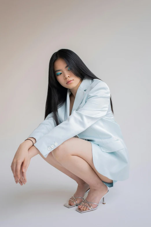 a woman sitting on the ground with her legs crossed, an album cover, inspired by helen huang, trending on unsplash, hyperrealism, wearing a light blue suit, blue long hair, in a photo studio, wearing off - white style