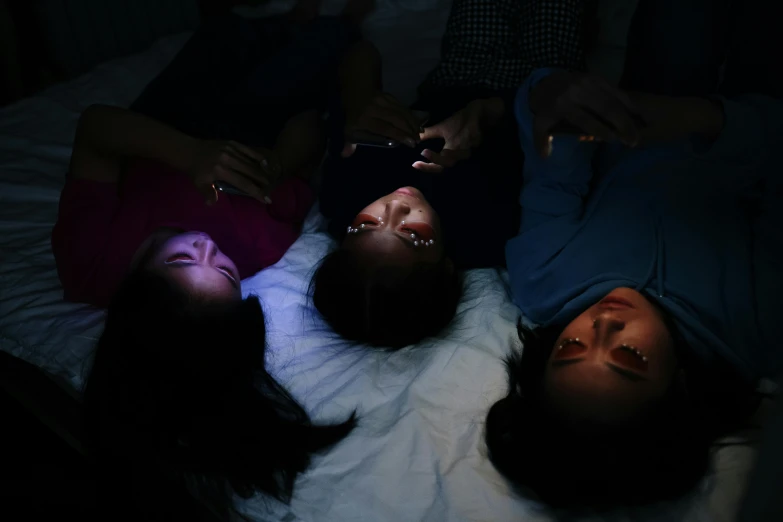 a group of people laying on top of a bed, trending on pexels, hyperrealism, thin healing glowing devices, three women, phone photo, asian descend