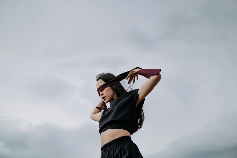 a woman standing on top of a lush green field, an album cover, trending on pexels, aestheticism, black blindfold, ninja outfit, grey sky, avatar image