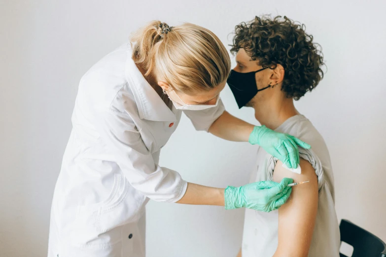 a woman getting a vaccine from a doctor, a photo, by Emma Andijewska, pexels, renaissance, haze over the shoulder shot, plain background, profile pic, construction