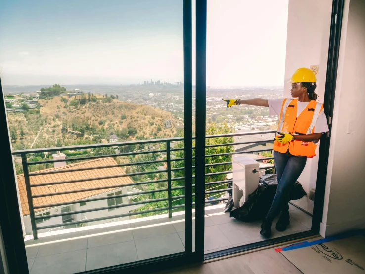 a man standing on top of a balcony next to a window, yellow hardhat, mulholland drive, developers, instagram post