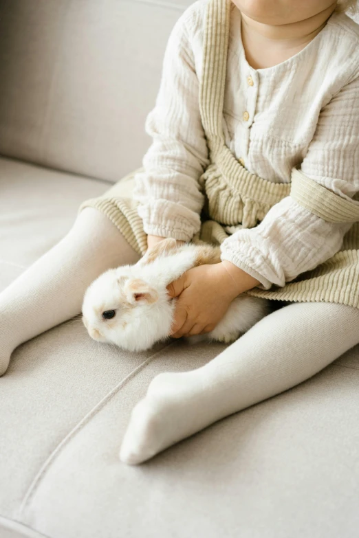 a little girl sitting on a couch holding a bunny, pexels contest winner, white tights, japanese, 1 2 9 7, gif
