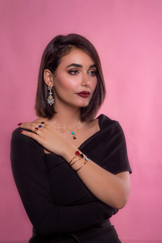 a woman in a black dress posing for a picture, by Julia Pishtar, hurufiyya, bracelets and necklaces, multi colour, ameera al taweel, earrings