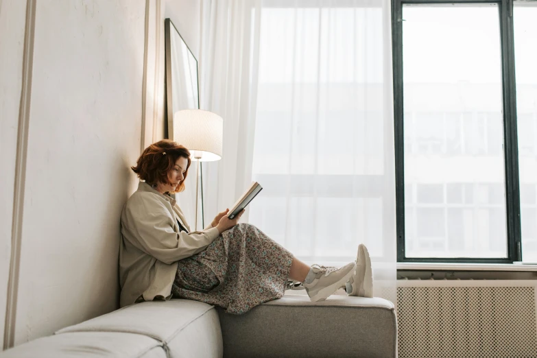 a woman sitting on a couch reading a book, pexels contest winner, sitting on edge of bed, profile image, casually dressed, scandinavian