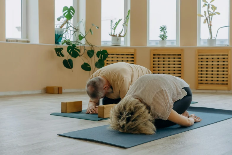 a man and a woman doing yoga together, by Emma Andijewska, head bowed slightly, low quality photo, background image, low ceiling