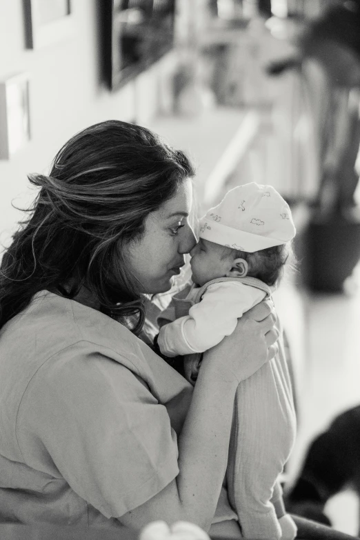 a black and white photo of a woman holding a baby, a black and white photo, pexels, happening, mirka andolfo, hospital bound, 8k 50mm iso 10, brown