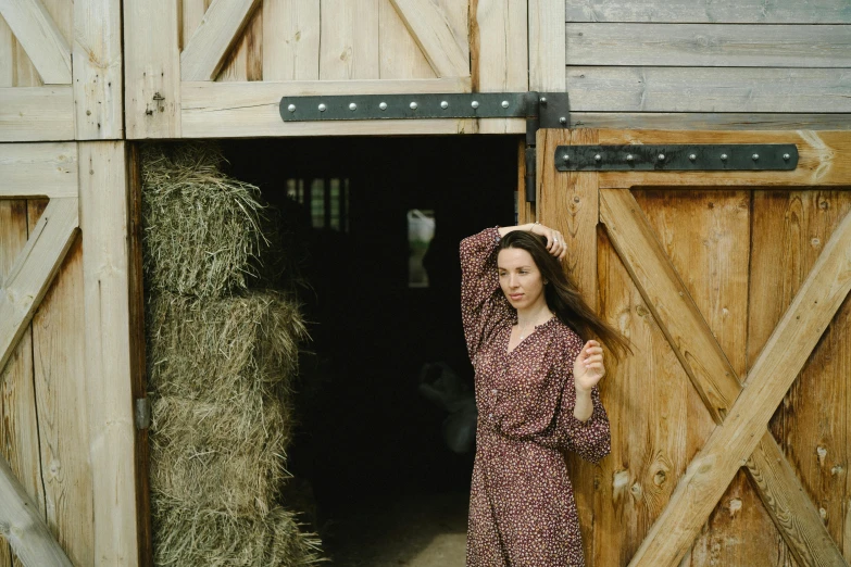 a woman standing in front of a barn door, by Emma Andijewska, pexels contest winner, patterned clothing, hay, valentin serov style, high resolution image