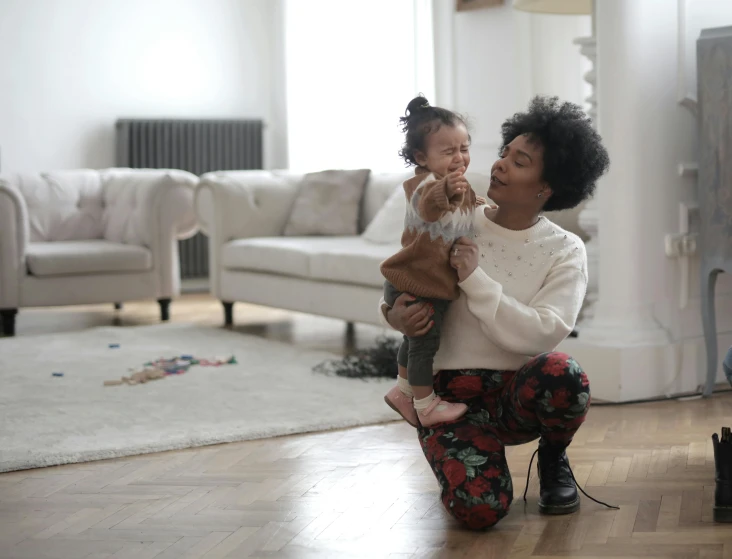 a woman holding a baby in a living room, pexels contest winner, hugging her knees, varying ethnicities, 1 5 0 4, thumbnail