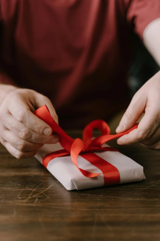 a person wrapping a gift with a red ribbon, manly, maintenance, square, paul barson