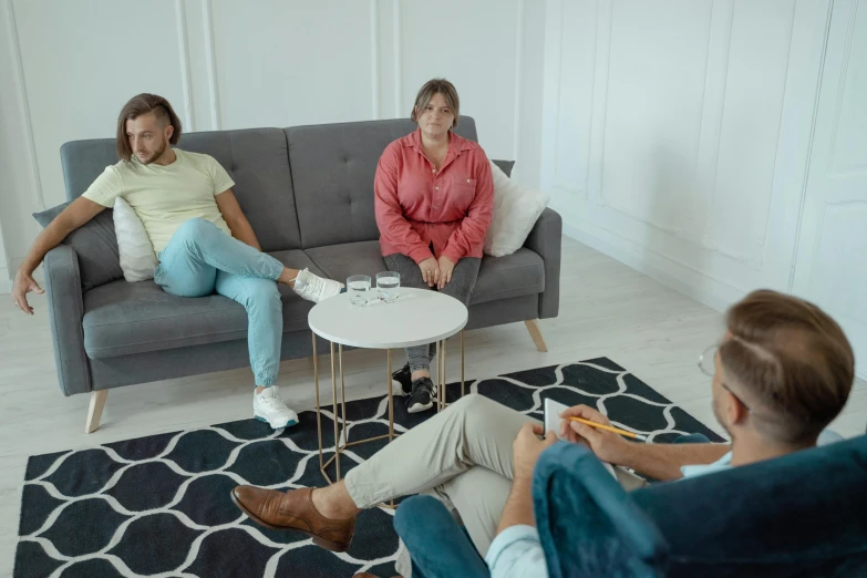 a group of people sitting on a couch in a living room, on a white table, kenopsia, multiple stories, mental health