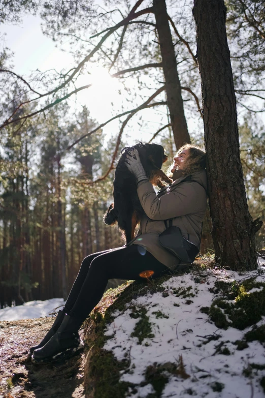 a woman sitting on a rock in the woods, by Emma Andijewska, pexels contest winner, wearing hunter coat, hugging, paws on head, climbing a tree