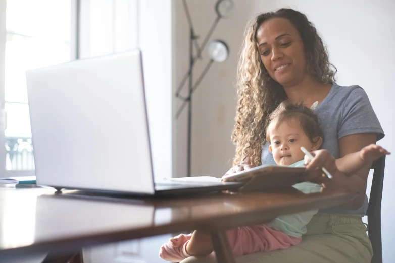 a woman sitting in front of a laptop with a baby on her lap, te pae, middle of the page, avatar image, unblur