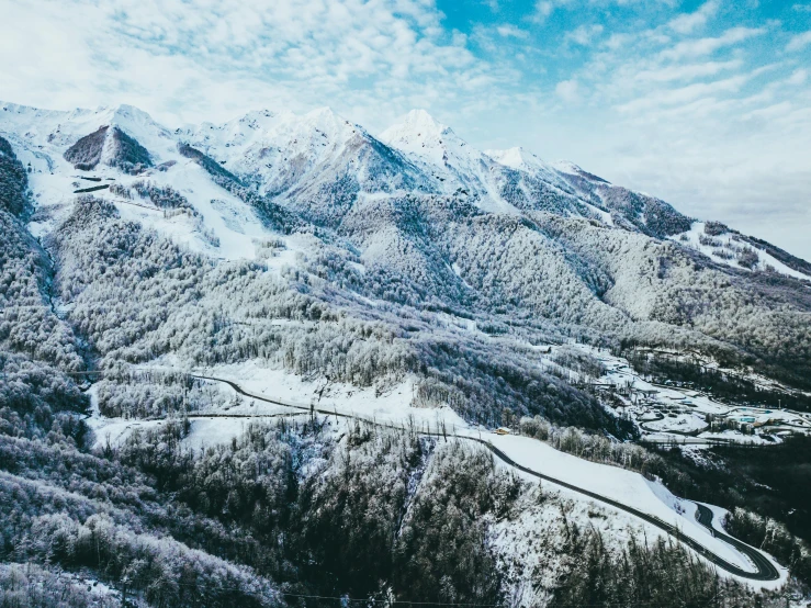 a large mountain covered in snow next to a forest, by Matthias Weischer, pexels contest winner, bird eye view, snowy italian road, thumbnail, lush forest in valley below