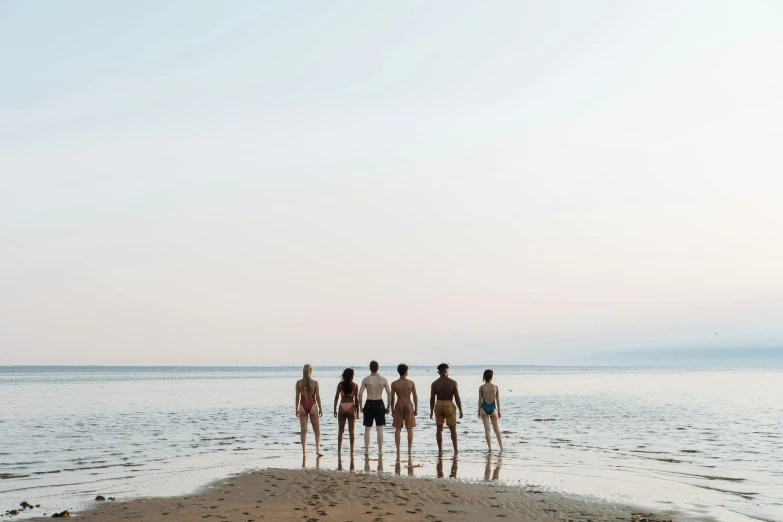 a group of people standing on top of a sandy beach, by Caro Niederer, unsplash, minimalism, swimming, calm evening, eight eight eight, ayne haag