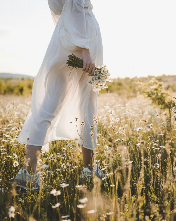 a woman in a white dress standing in a field, trending on unsplash, happening, pregnant, carrying flowers, bare feet in grass, early evening
