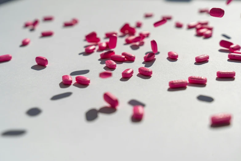 a white table topped with lots of pink pills, a microscopic photo, by Sebastian Vrancx, pexels, plasticien, alessio albi, red velvet, medium long shot, magenta