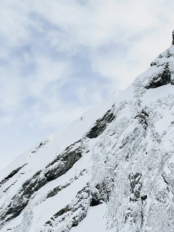 a man riding a snowboard down the side of a snow covered slope, by Johannes Voss, pexels contest winner, towering above a small person, rocky cliff, slightly pixelated, panoramic shot