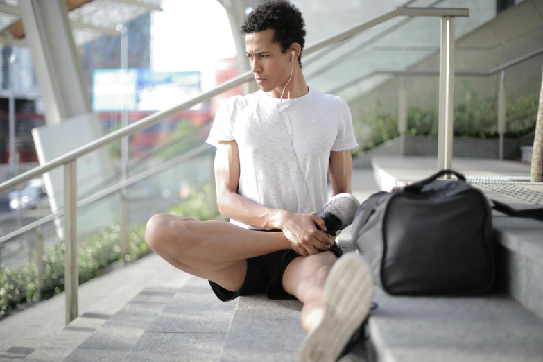 a man sitting on the steps of a building, wearing fitness gear, zaha hadi, candid photograph, lean man with light tan skin
