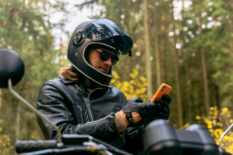 a person on a motorcycle looking at a cell phone, caramel. rugged, thumbnail, outdoor, avatar image