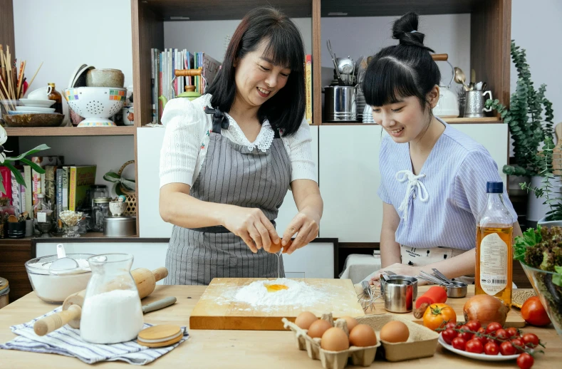 a couple of women standing next to each other in a kitchen, inspired by Yukimasa Ida, pexels contest winner, ingredients on the table, heonhwa choe, youtube thumbnail, good housekeeping