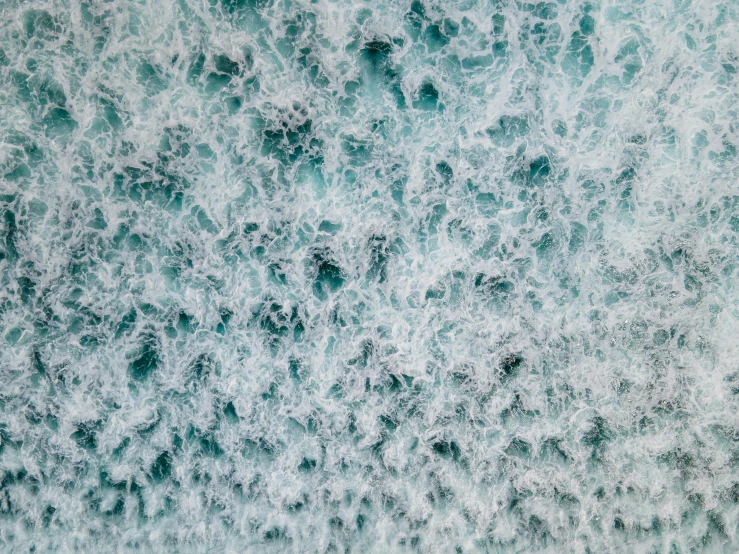 a person riding a surfboard on top of a wave, inspired by Andreas Gursky, pexels, extremely detailed water texture, aquamarine, foamy bubbles, photograph from above