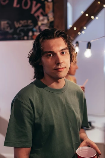a man in a green shirt holding a red cup, an album cover, by Adam Dario Keel, trending on unsplash, photorealism, mid - length hair, lovingly looking at camera, turtle, xqc