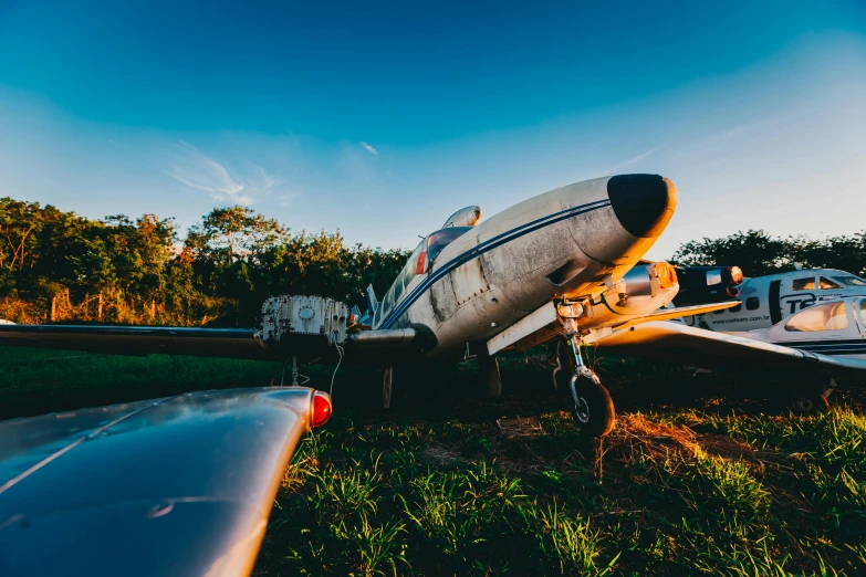 a small airplane sitting on top of a lush green field, unsplash, auto-destructive art, twilight junkyard, profile image, wide angle shots, retro spaceships parked outside