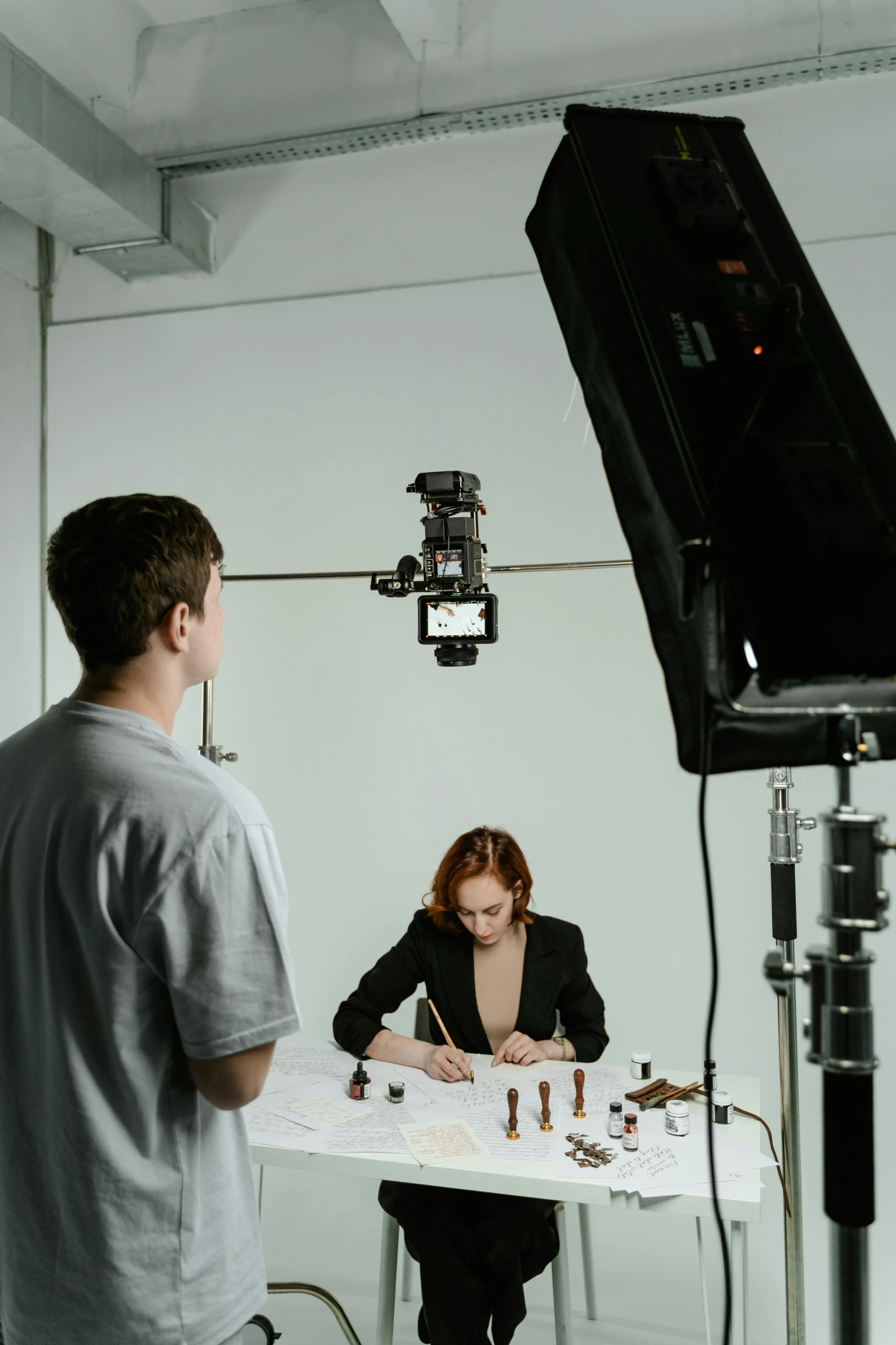 a man and a woman sitting at a table in front of a camera, product shoot, production ig, back facing the camera, low quality photo