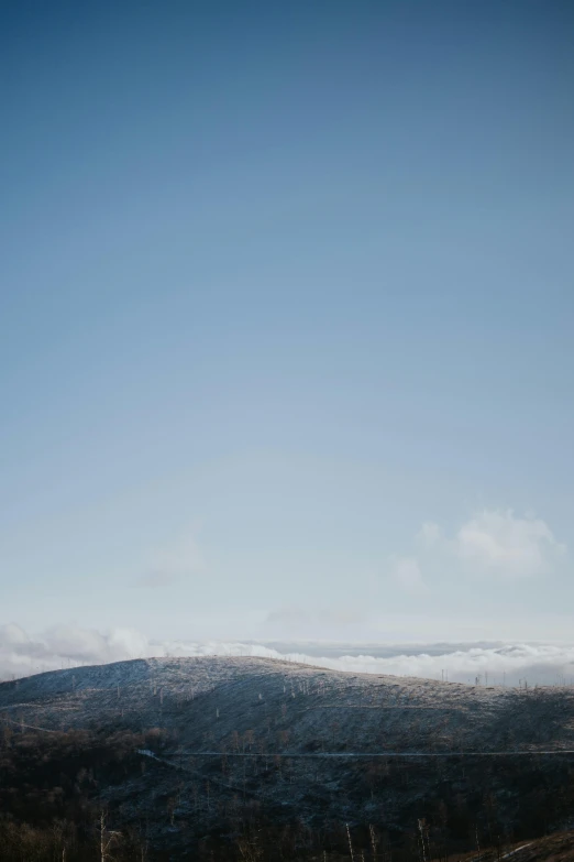 a man riding a snowboard down a snow covered slope, trending on unsplash, sparse mountains on the horizon, view above the clouds, scotland, minimalist photo