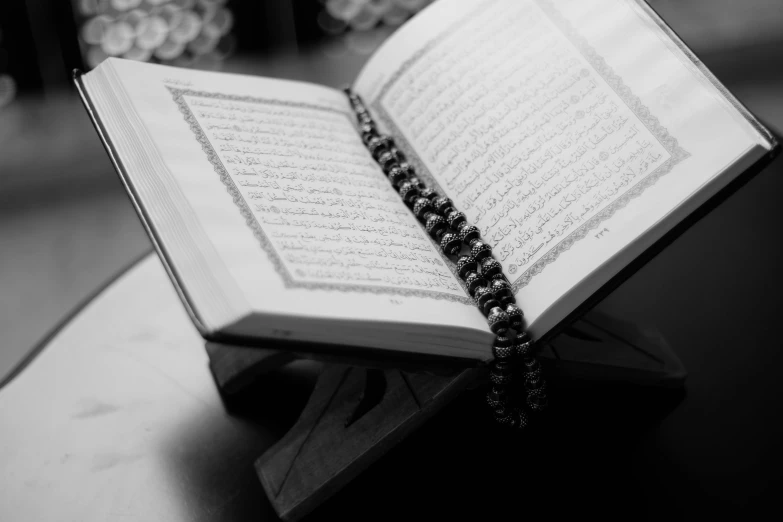 a close up of an open book on a table, a black and white photo, hurufiyya, islamic art, uploaded, pray, iray